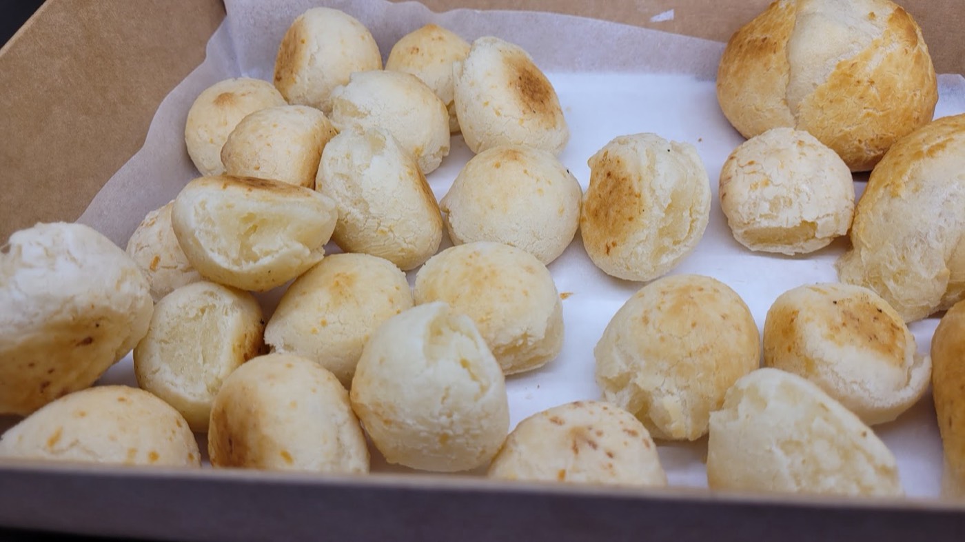 A box of golden pão de queijo, fresh from the oven